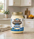 A jar of Condensedable Deluxe Condensed Non-Fat Milk sits on a kitchen counter with a blurred kitchen background.