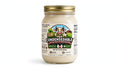 A 10 oz glass jar of Condensedable Sweetened Creamery Vanilla Sweetened Condensed Milk with a gold metal lid and a colorful cartoon cow label, set against a plain white background.